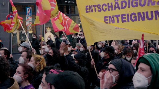 a crowd marches with banners on May Day anti-capitalism protest in Berlin